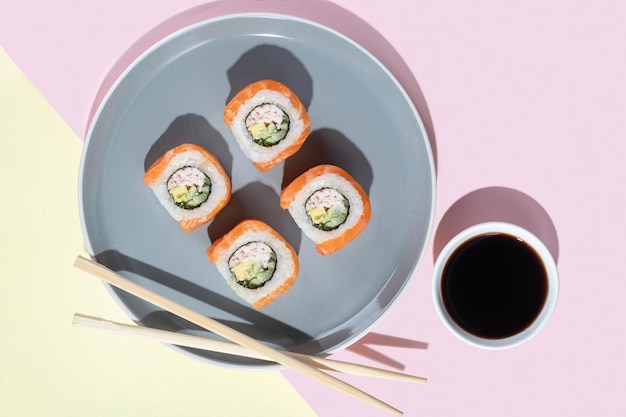 Sushi japonés con rollos de dragón de salmón sobre un fondo amarillo brillante Arte pop Sabrosos bocadillos en un plato gris y palillos