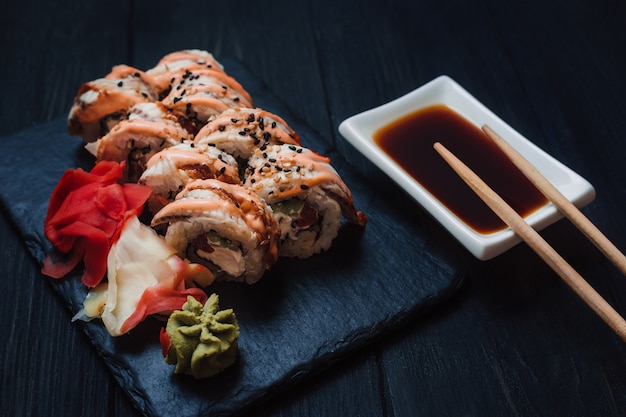 Sushi japonés con salsa de soja y wasabi en placa de piedra negra