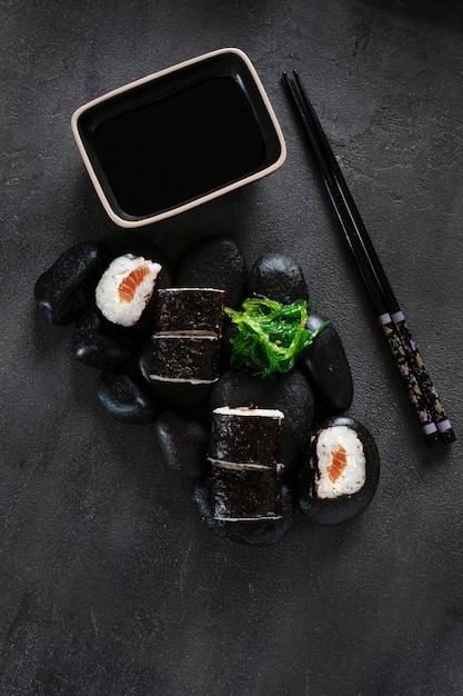 Sushi japonés servido sobre piedras negras. Vista superior, de cerca sobre fondo oscuro.