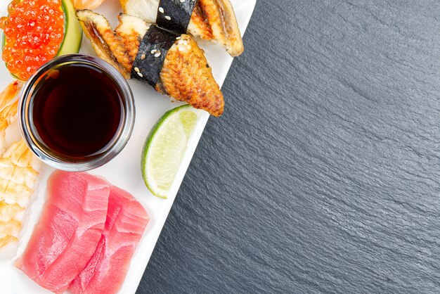 Sushi japonés tradicional en un plato blanco sobre una piedra negra