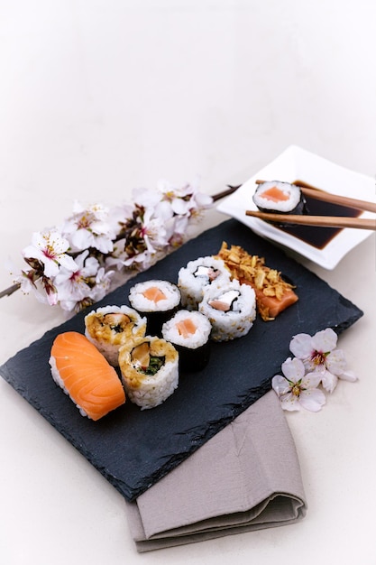 Sushi legte auf Tafel und Essstäbchen, die das Sushi nehmen, um es in Soja einzutauchen