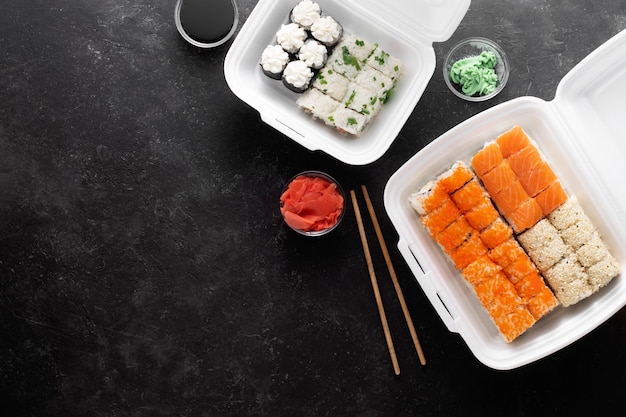 Sushi Lieferung. Asiatisches Essen in Plastikbehältern auf einem schwarzen Hintergrund