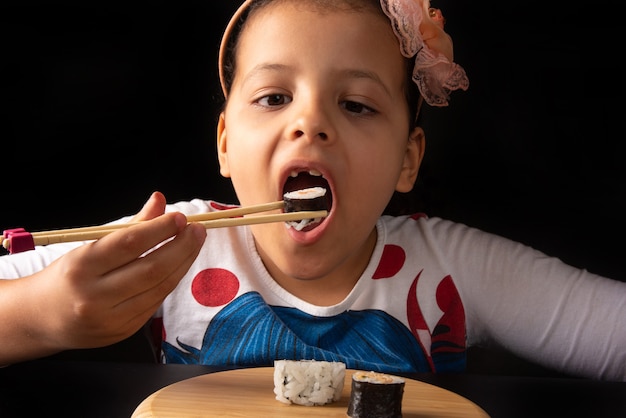 Sushi, linda garota comendo sushi com pauzinhos