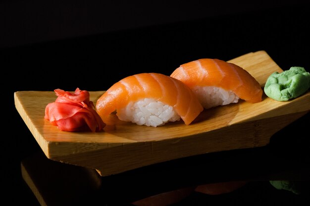 Sushi mit Reis und Wasabi auf einem Holzbrett auf dunklem Hintergrund