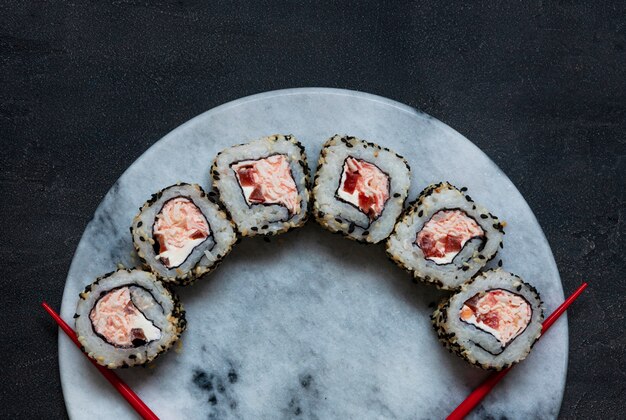 Sushi de mousse de carne de cangrejo japonés sobre tabla de piedra de mármol con palillos