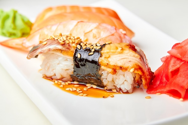 Sushi nigiri con anguila ahumada, salsa unagi y semillas de sésamo tostadas. Primer plano, enfoque selectivo