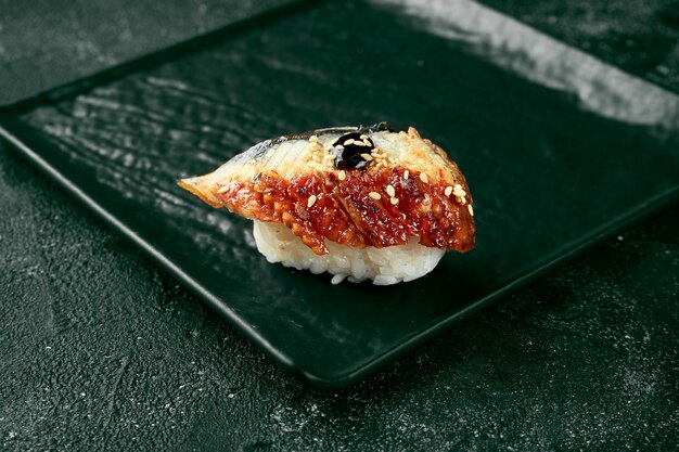 Sushi nigiri con anguila en una pizarra con jengibre y wasabi. Cocina Japonesa. Entrega de comida. Fondo negro