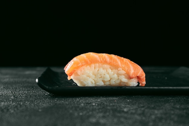 Sushi nigiri con salmón en una pizarra. Cocina Japonesa. Entrega de comida. Fondo negro