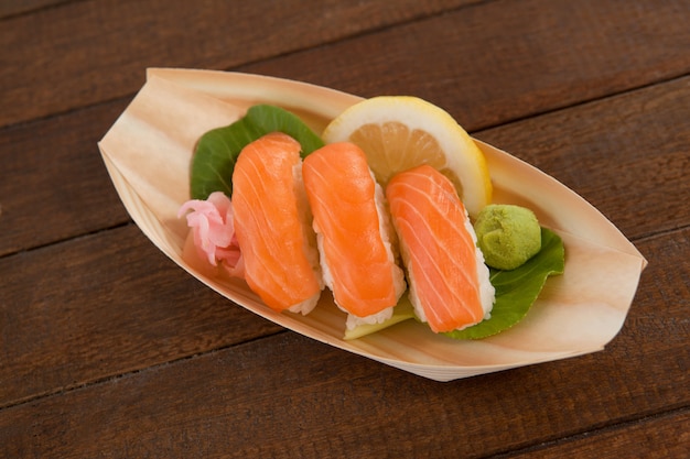 Sushi nigiri três servido no prato de barco de madeira