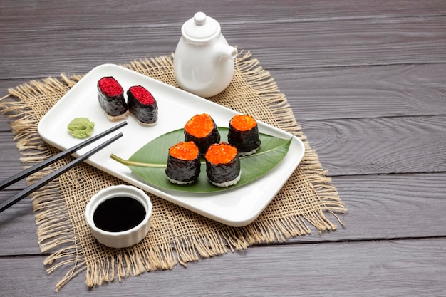 Sushi nori con palillos negros de caviar en plato blanco