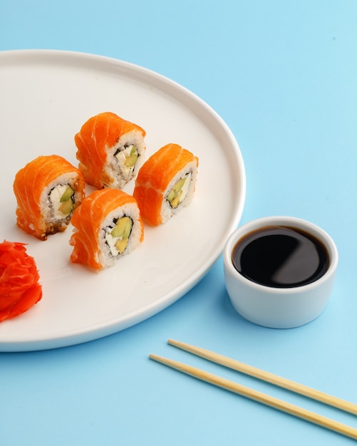 Sushi rola em um prato branco sobre um azul.