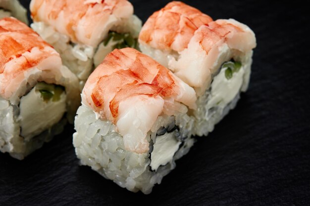 Sushi rola Filadélfia com sementes de gergelim de pepino de queijo creme de caranguejo de neve isoladas em fundo preto cozinha oriental japonesa