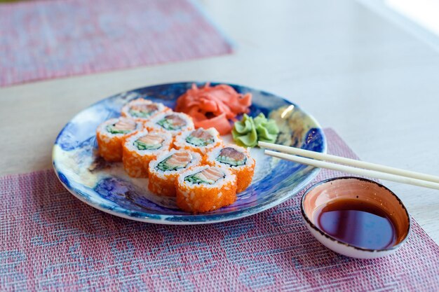 Sushi roll Filadelfia con salmón ahumado anguila queso crema de aguacate en plato azul Menú de sushi california rollSushi con palillos comida japonesa en el restaurante