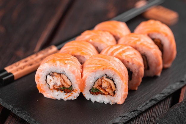 Foto sushi roll maguro con salmón ahumado anguila aguacate y tobiko en tablero negro de primer plano menú de sushi comida japonesa