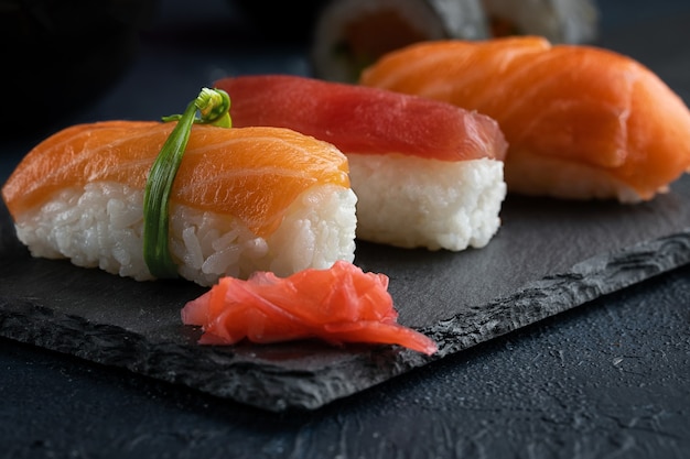 Foto sushi roll, nigiri mit lachs, thunfisch, avocado und gemüse auf schwarzem felsen