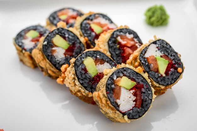 Sushi-Rolle aus frischem Lachs-, Avocado- und Frischkäse mit schwarzem Reis