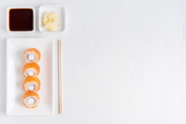 Foto sushi-rolle aus rohem lachs, reis, creme-käse und nori, serviert mit sojasauce