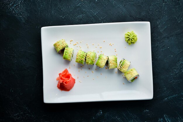 Sushi-Rolle mit Avocado-Gurke und Tomate Japanische Küche Draufsicht auf schwarzem Hintergrund