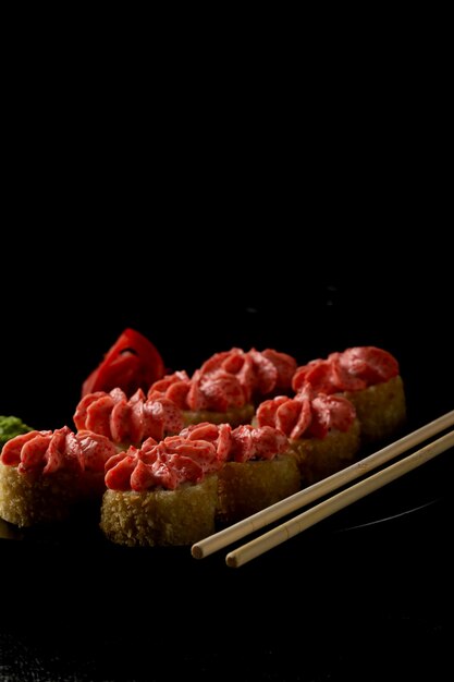 Sushi-Rolle mit Lachs, Räucheraal, Avocado, Frischkäse auf schwarzem Hintergrund