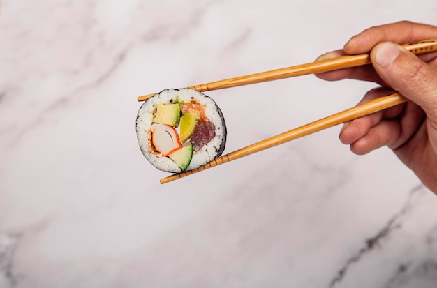 Sushi-Rolle mit Lachs-Thunfisch-Krabben und Avocado mit Essstäbchen