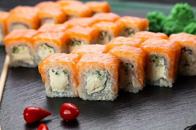 Sushi-Rollen auf dunklem Hintergrund, dekoriert mit Bambusblättern und Essstäbchen