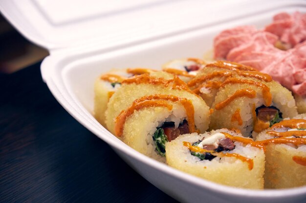 Sushi-Rollen in einem weißen Plastikbehälter Lebensmittellieferung