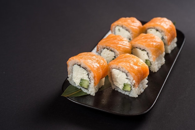 Sushi-Rollen in einer schwarzen Platte auf dunklem Hintergrund hautnah