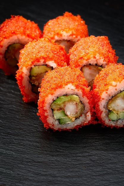 Sushi-Rollen Kalifornien mit Schneekrabben, Frischkäse, Gurke, Sesam und Masago-Kaviar auf schwarzem Hintergrund mit Reflektion Sushi-Menü japanische Küche