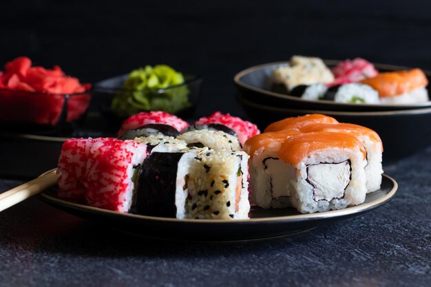 Sushi-Rollen liegen auf schwarzen Platten auf dunkler Hintergrundseitenansicht horizontal