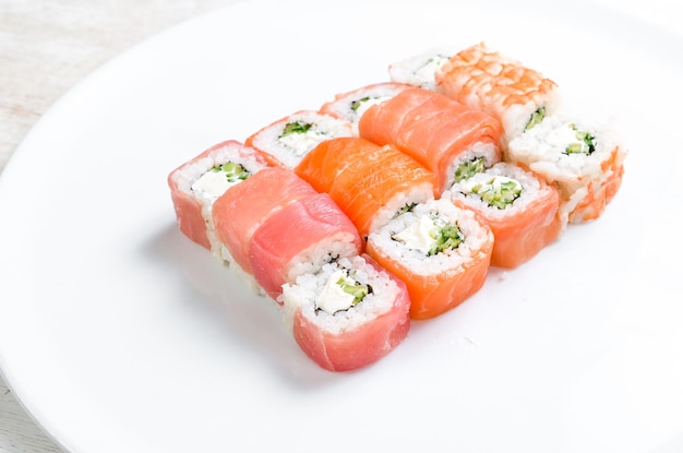 Sushi-Rollen mit Avocado und Lachs auf einem weißen Teller Draufsicht auf weißem Hintergrund