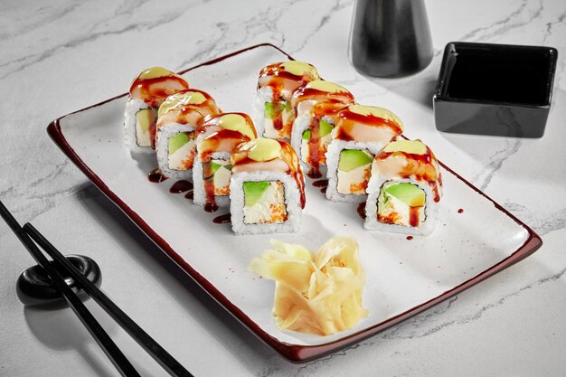 Foto sushi-rollen mit frischkäse-avocado-tobiko-butterfisch-mayonnaise und unagi-sauce