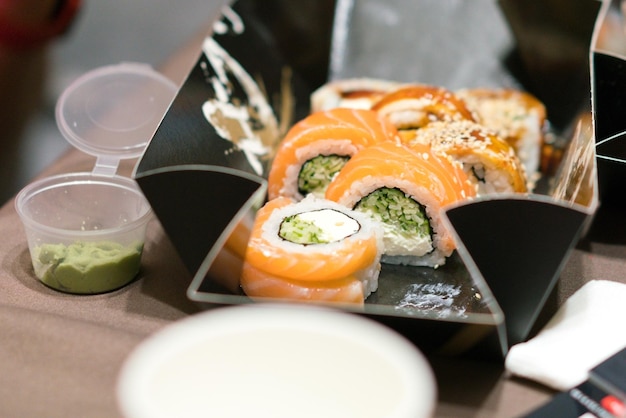 Sushi-Rollen mit Lachs, Gurke und Sesam in einer schwarzen Verpackung. Meeresfrüchte Algen Asien frisch Maki Teller traditionell Tradition Zubereitung Creme Delikatesse gesund