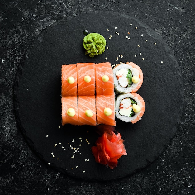 Sushi-Rollen mit Lachs Traditionelles japanisches Essen auf einer schwarzen Steinplatte