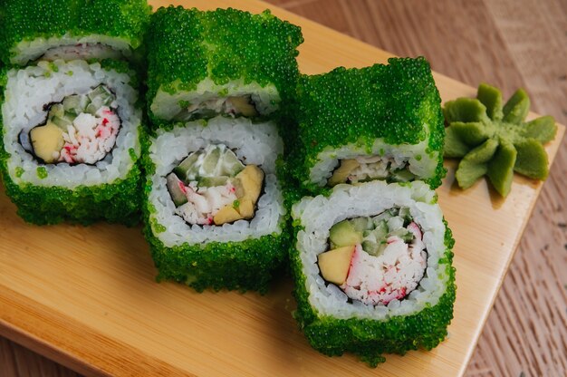 Sushi-Rollen mit Tobiko Green Caviar auf Holzbrett