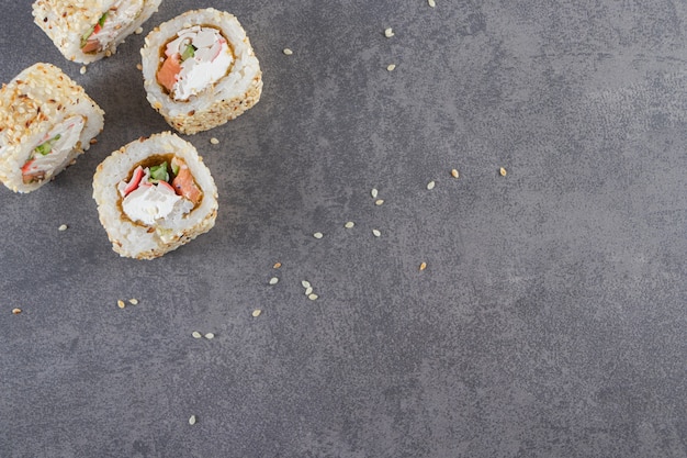 Sushi-Rollen, Sojasauce, Wasabi und eingelegter Ingwer auf Steinhintergrund.