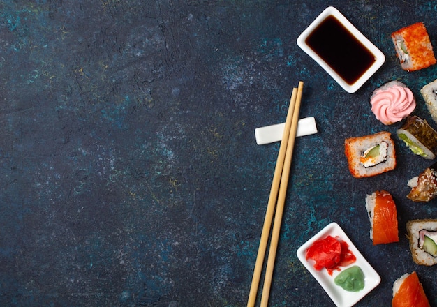 Sushi-Rollenset mit Essstäbchen und Sojasauce auf blauem Hintergrund Draufsicht des Kopierbereichs