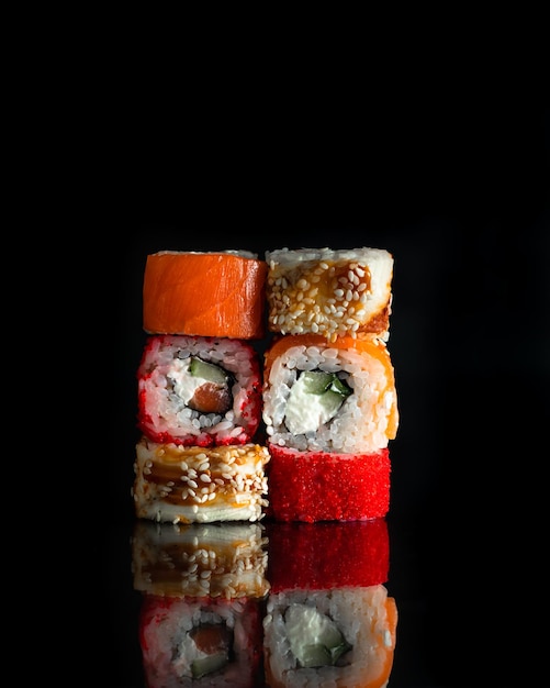 Foto sushi rolls set maki philadelphia y california rolls sobre un fondo negro