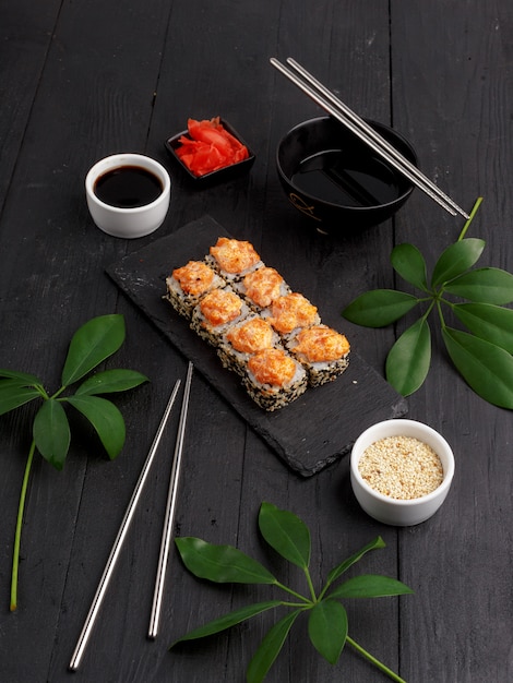 Sushi rollt auf farbigen Platten auf einem schwarzen Hintergrund