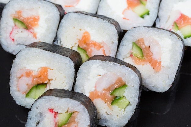 Sushi rollt Futo Maki auf schwarzem Hintergrund.