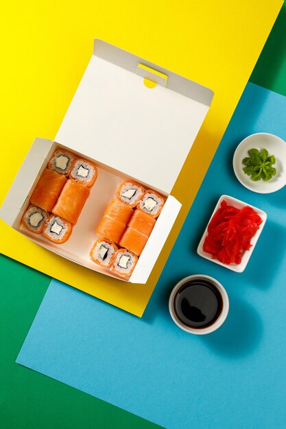 Sushi-Set auf buntem, hellem Hintergrund, serviert mit Sojasauce, Wasabi und IngwerxA