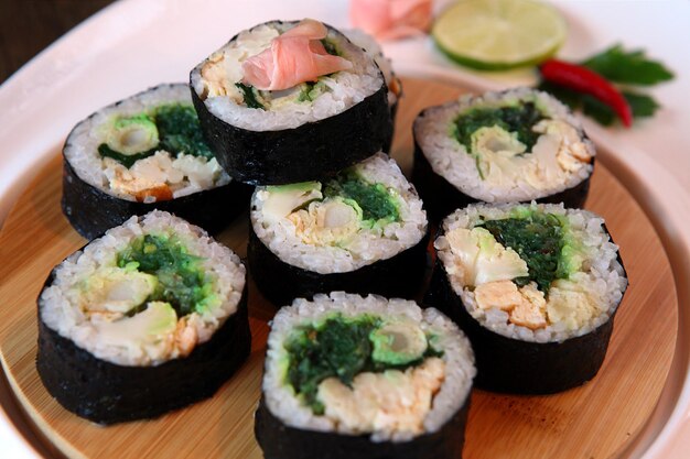 Sushi Set - Diferentes tipos de Maki Sushi y Nigiri Sushi con palillos de madera. Servido en mesa de madera oscura en estilo rústico.