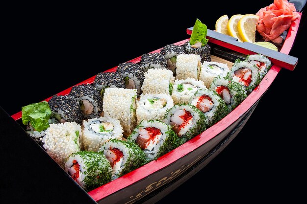 Sushi-Set in einem Holzboot auf schwarzem Hintergrund