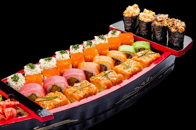 Sushi-Set in einem Holzboot auf schwarzem Hintergrund