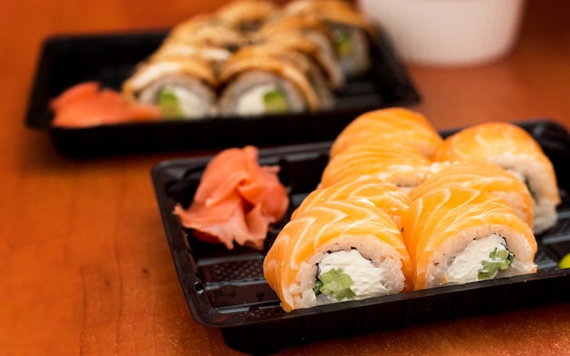 Sushi-Set in Plastikbox mit Lachs, Garnelen, Wasabi und Ingwer. Traditionelle japanische Küche. Lieferservice-Konzept für Lebensmittel.