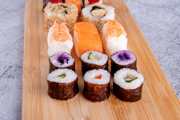 Sushi-Set mit Essstäbchen und Soja auf einer Holzplatte essfertig auf grauem Hintergrund