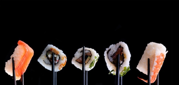 Sushi-Set mit Stäbchen auf schwarzem Hintergrund. Platz für Text. Hintergrund für Menü