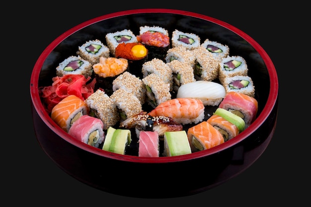 Sushi Set rollos de nigiri y sashimi servidos en el tradicional plato redondo de Sushioke negro de Japón Sobre fondo oscuro