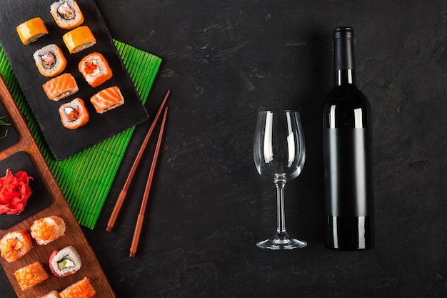 Sushi set sashimi e sushi rolls, garrafa de vinho e um copo servido na ardósia de pedra