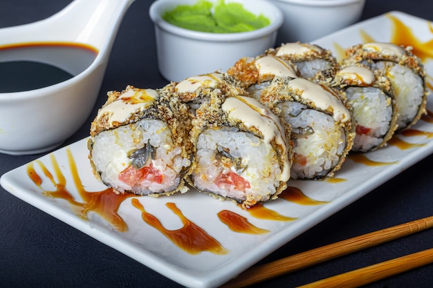 Foto sushi sets uramaki, california, filadelfia, en un plato blanco. cerca de jengibre y wasabi.