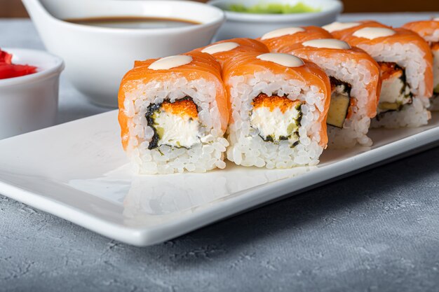 Sushi setzt Nigiri, Uramaki, Kalifornien, Philadelphia, auf einen weißen Teller. In der Nähe Ingwer und Wasabi.